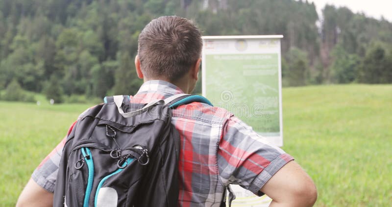 Dorosły mężczyzna z plecakiem czyta pointerów w górach