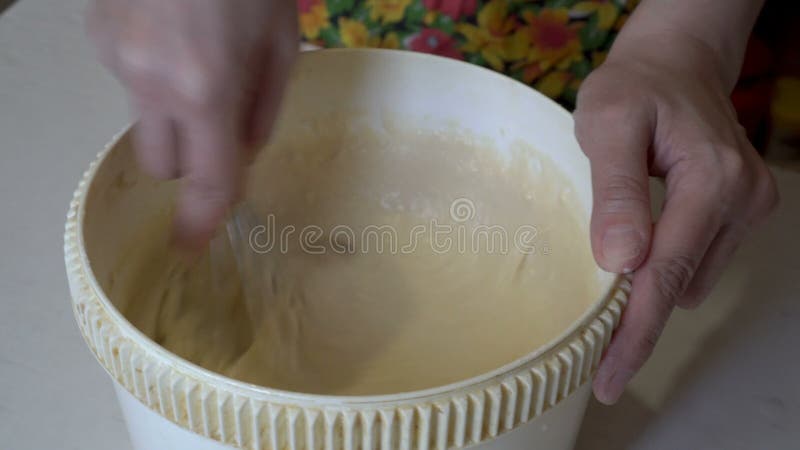 Dorosła kobieta szybko wbija batter w białą miskę w kuchni domowej. przygotowanie słodkiej deseru. zamykanie