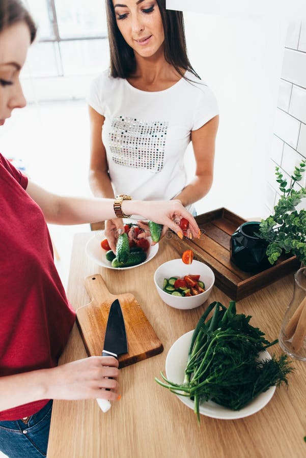 Dos amigos de muchachas que preparan la cena en la cocina que cocina la ensalada imágenes de archivo libres de regalías Dos amigos de muchachas que preparan la cena en la cocina que cocina la ensalada imágenes de archivo libres de regalías