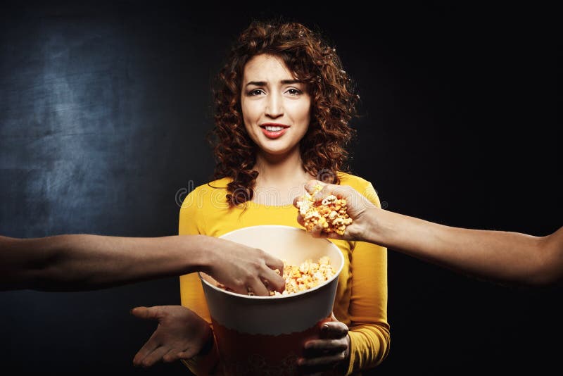 Dos amigos que toman las palomitas del cubo del ` s de la muchacha Emociones faciales negativas foto de archivo libre de regalías Dos amigos que toman las palomitas del cubo del ` s de la muchacha Emociones faciales negativas foto de archivo libre de regalías