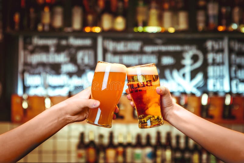 Dos amigos que tuestan con los vidrios de cerveza ligera en el pub Fondo hermoso del grano fino de Oktoberfest imagen de archivo libre de regalías Dos amigos que tuestan con los vidrios de cerveza ligera en el pub Fondo hermoso del grano fino de Oktoberfest imagen de archivo libre de regalías