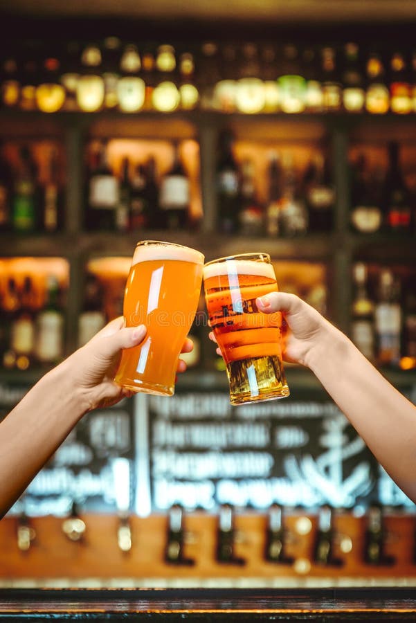 Dos amigos que tuestan con los vidrios de cerveza ligera en el pub Fondo hermoso del grano fino de Oktoberfest fotografía de archivo libre de regalías Dos amigos que tuestan con los vidrios de cerveza ligera en el pub Fondo hermoso del grano fino de Oktoberfest fotografía de archivo libre de regalías