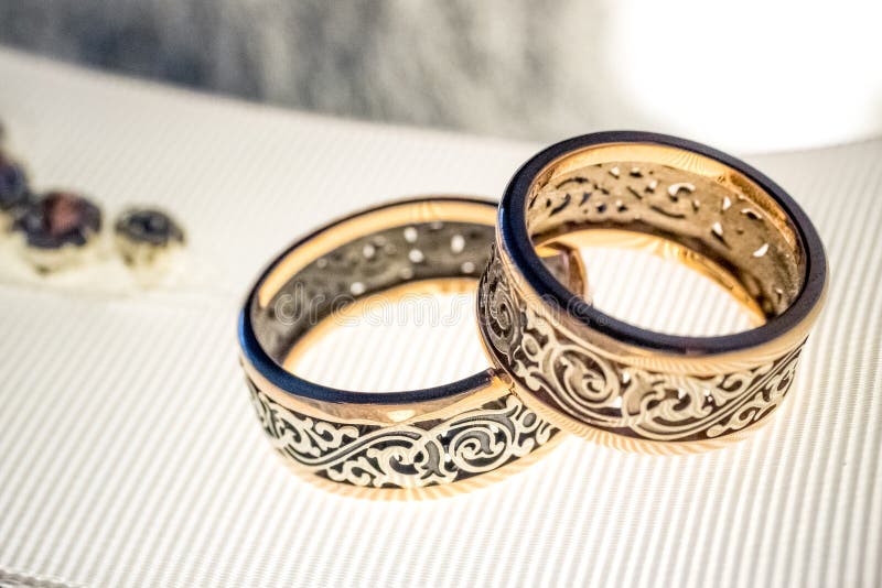 Dos anillos de bodas con diseño raro en la cinta amplia blanca imágenes de archivo libres de regalías Dos anillos de bodas con diseño raro en la cinta amplia blanca imágenes de archivo libres de regalías