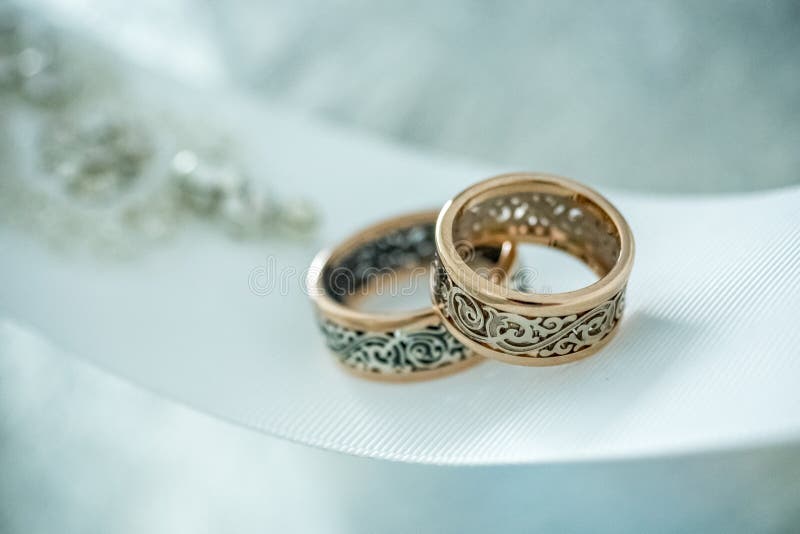 Dos anillos de bodas con diseño raro en la cinta amplia blanca foto de archivo libre de regalías Dos anillos de bodas con diseño raro en la cinta amplia blanca foto de archivo libre de regalías
