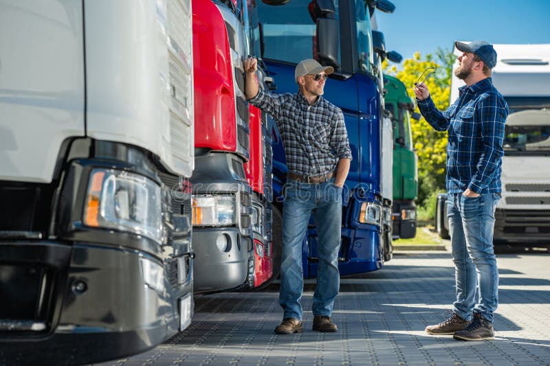 Dos camioneros parados al lado de una hilera de semicamiones foto de archivo libre de regalías