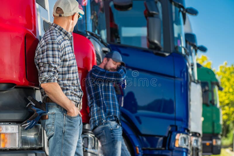 Dos camioneros parados al lado de una línea de camiones en un estacionamiento fotos de archivo libres de regalías