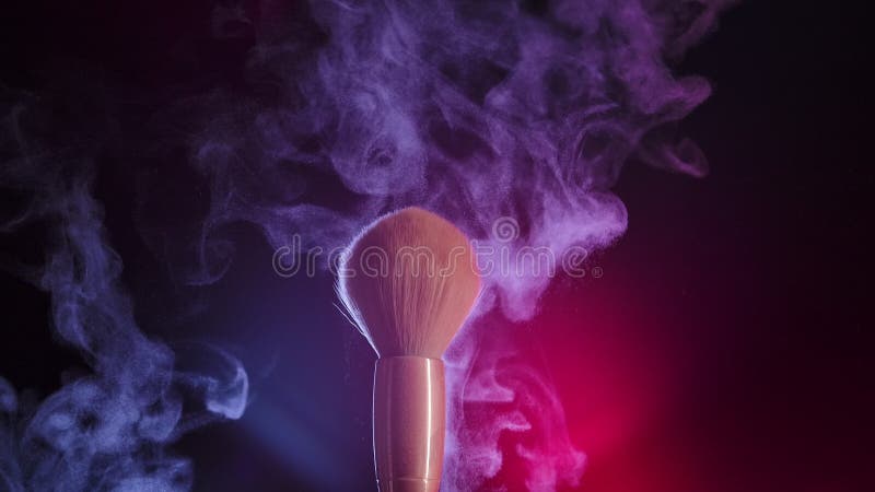 Dos cepillos de maquillaje se tocan entre sí para formar un intrincado remolino de partículas de polvo cosmético. primer plano de