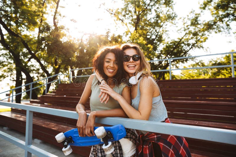 Dos chicas jóvenes alegres con el monopatín foto de archivo libre de regalías Dos chicas jóvenes alegres con el monopatín foto de archivo libre de regalías
