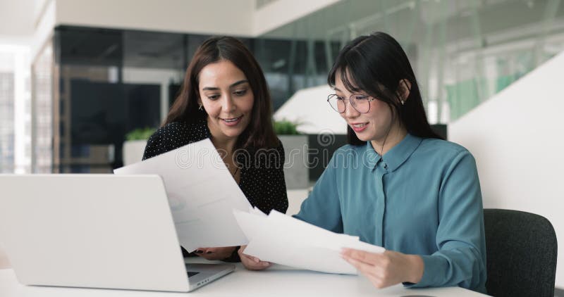 Dos colegas femeninas diversas y positivas analizando el informe de marketing en papel metrajes