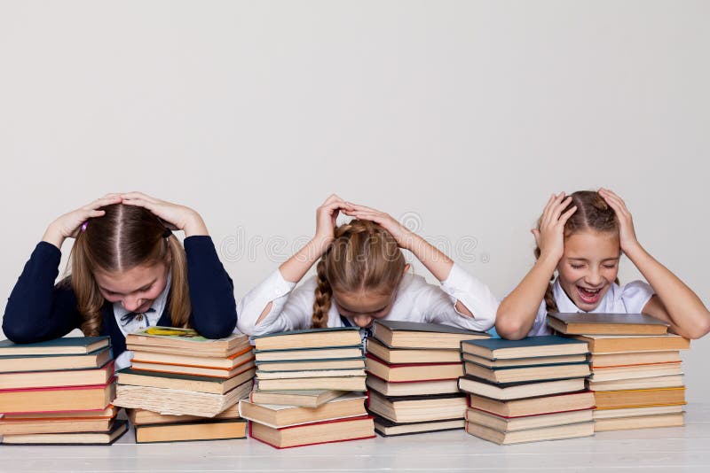 Dos colegialas de las muchachas se sientan con los libros en su escritorio en la lección en la escuela foto de archivo Dos colegialas de las muchachas se sientan con los libros en su escritorio en la lección en la escuela foto de archivo