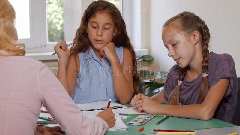 Dos colegialas que disfrutan de su clase de arte con el profesor en la escuela imagen de archivo Dos colegialas que disfrutan de su clase de arte con el profesor en la escuela imagen de archivo