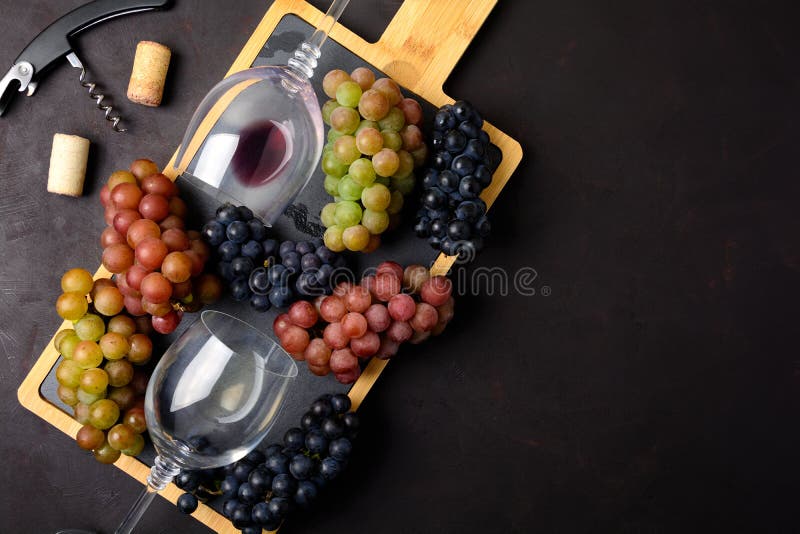 Dos copas con el vino blanco rojo y, las uvas, el sacacorchos y los corchos mintiendo en fondo de madera oscuro fotos de archivo libres de regalías Dos copas con el vino blanco rojo y, las uvas, el sacacorchos y los corchos mintiendo en fondo de madera oscuro fotos de archivo libres de regalías