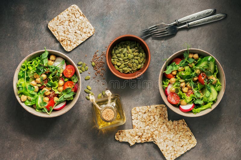 Dos cuencos de vegano y de ensalada dietética vegetariana de verduras frescas, de garbanzos y de semillas en un fondo rústico osc fotos de archivo Dos cuencos de vegano y de ensalada dietética vegetariana de verduras frescas, de garbanzos y de semillas en un fondo rústico osc fotos de archivo