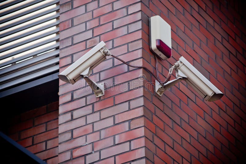 Two security cameras attached on brick wall. Two security cameras attached on brick wall