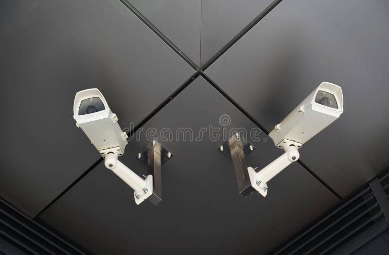 Two surveillance cameras mounted on outdoor ceiling. Two surveillance cameras mounted on outdoor ceiling