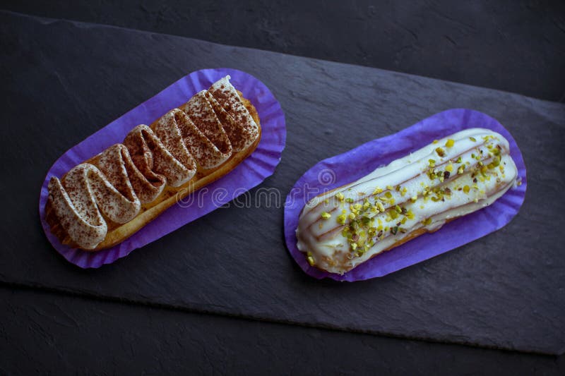 Dos deliciosos pasteles de eclair con sabor a tiramisú y pistacho imagen de archivo