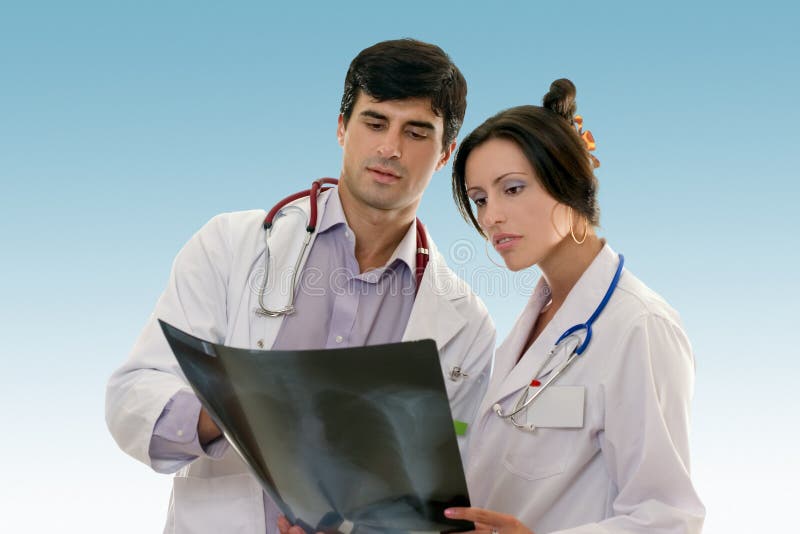 Male and female doctors confer over the results of a patient chest x-ray. Male and female doctors confer over the results of a patient chest x-ray.