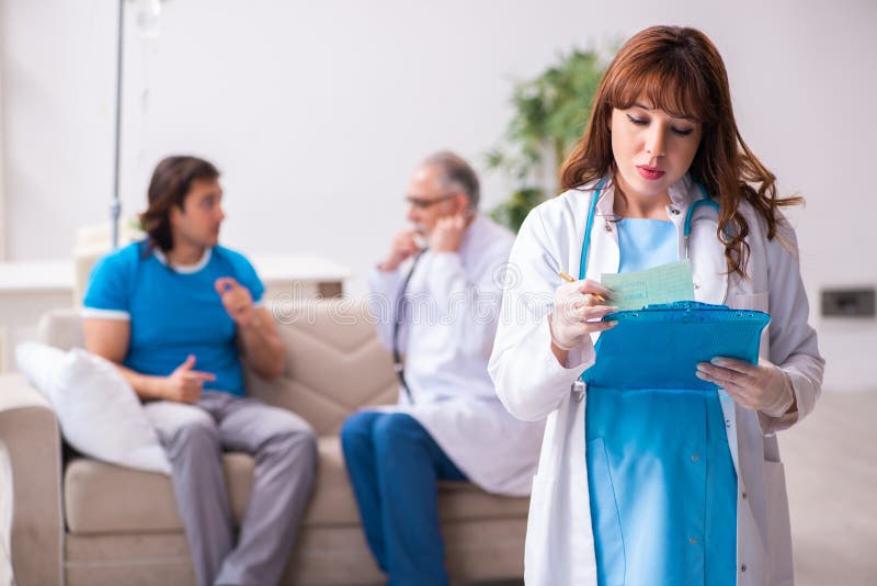 Dos Doctores Visitando a Un Joven Enfermo En Casa Foto de archivo