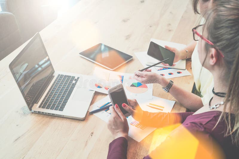 Dos empresarias jovenes se están sentando en la tabla y están discutiendo el plan empresarial fotos de archivo Dos empresarias jovenes se están sentando en la tabla y están discutiendo el plan empresarial fotos de archivo