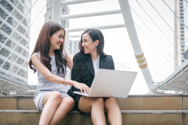 Dos empresarias que trabajan en el ordenador portátil con el em divertido feliz imagenes de archivo Dos empresarias que trabajan en el ordenador portátil con el em divertido feliz imagenes de archivo