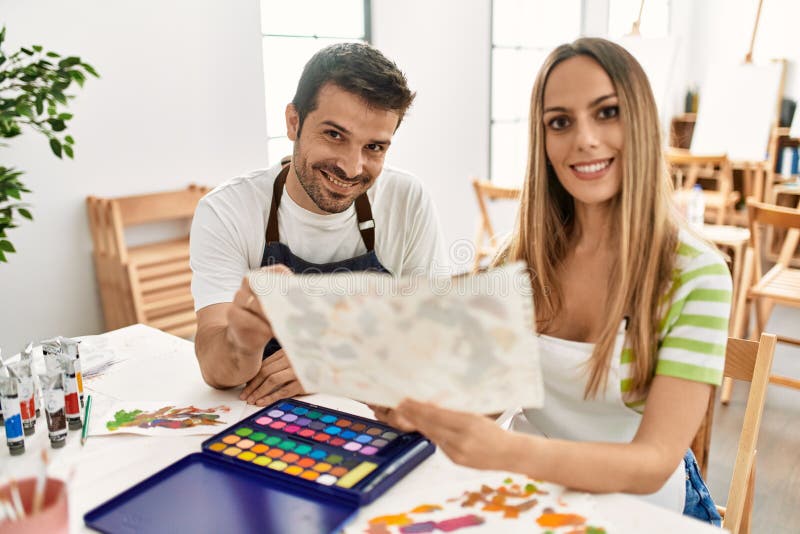 Dos estudiantes sonriendo con pintura feliz sentados en la mesa en la escuela de arte imagenes de archivo