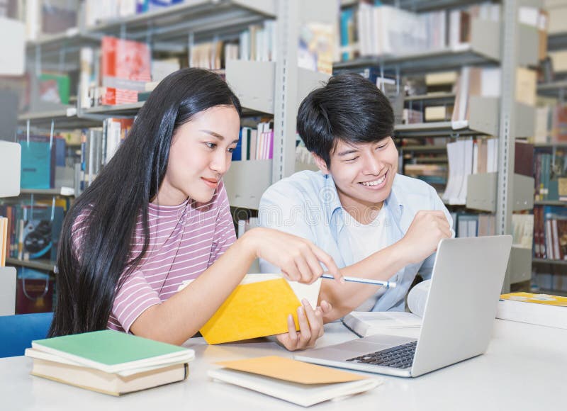 Dos estudiantes universitarios asiáticos que usan el ordenador portátil en la biblioteca fotografía de archivo libre de regalías Dos estudiantes universitarios asiáticos que usan el ordenador portátil en la biblioteca fotografía de archivo libre de regalías