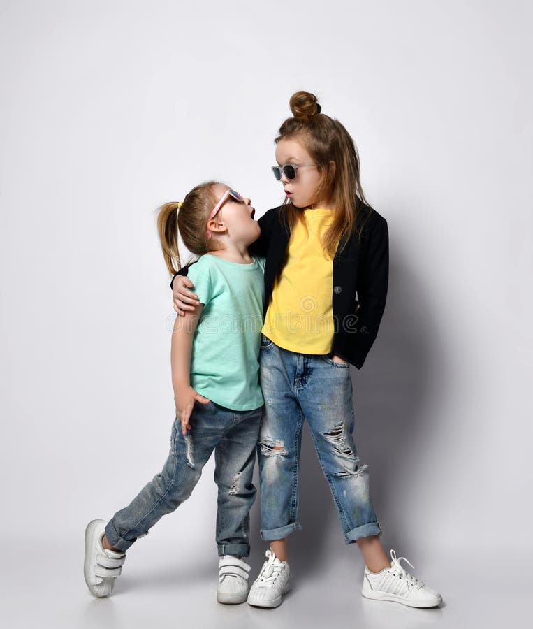 Dos Hermanas De Niñas De Niños Fruncidos Con Ropa Elegante Gafas De Sol Y Zapatillas De Deporte Se Unen Y Se Miran Entre Sí Foto de archivo - Imagen de ropa,