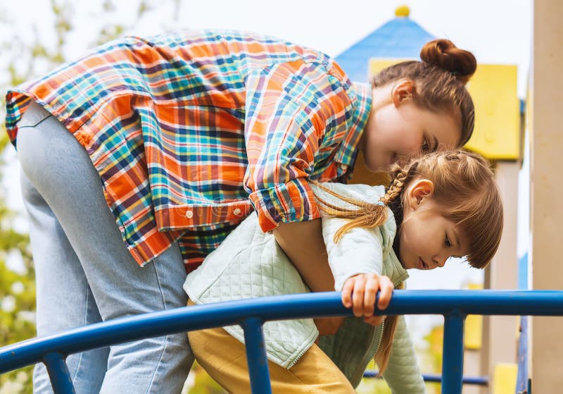 Dos hermanas felices pasan tiempo en el patio. la hermana mayor ayuda a la hermana menor a subir las escaleras. una niña joven est imagen de archivo libre de regalías