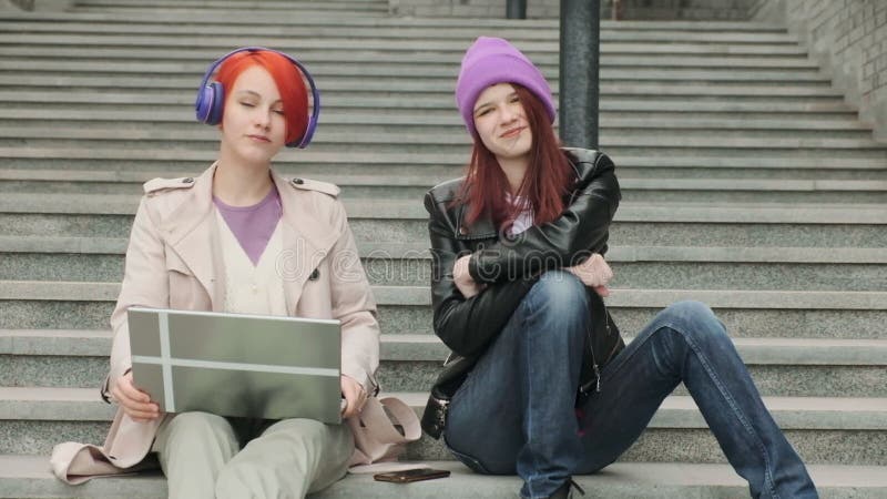 Dos hermosos amigos jóvenes están sentados y usando un portátil para el entretenimiento