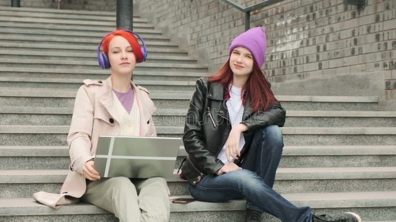 Dos hermosos amigos jóvenes están sentados y usando un portátil para el entretenimiento