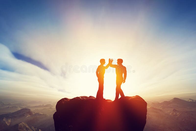 Dos hombres, amigos altos cinco encima de las montañas acuerdo