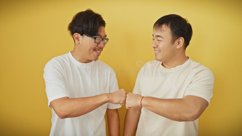 Dos hombres asiáticos con camisas blancas tropezando con un fondo aislado amarillo fotos de archivo