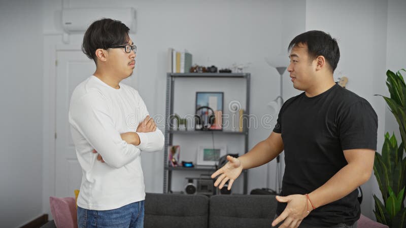 Dos hombres asiáticos conversan en una sala de estar moderna evocando un sentido de amistad informal o discusión en interiores imagen de archivo libre de regalías