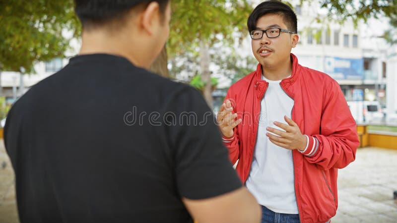 Dos hombres asiáticos conversando al aire libre en un parque urbano verde creando una sensación de camaradería imágenes de archivo libres de regalías