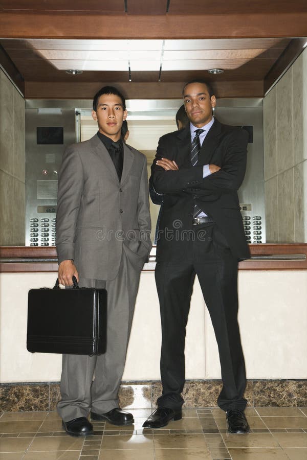 Dos hombres de negocios que se colocan en pasillo fotografía de archivo Dos hombres de negocios que se colocan en pasillo fotografía de archivo