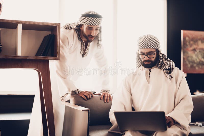 Dos hombres de negocios árabes que miran en el ordenador portátil junto imagenes de archivo