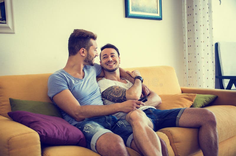 Dos hombres gay en el sofá que abrazan en casa imágenes de archivo libres de regalías Dos hombres gay en el sofá que abrazan en casa imágenes de archivo libres de regalías