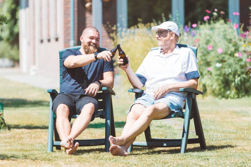 Dos Hombres Sonrientes Jóvenes Y Viejos Bebiendo Cerveza En El Jardín De  Verano Imagen de archivo - Imagen de aferrarse, botella: 191662765