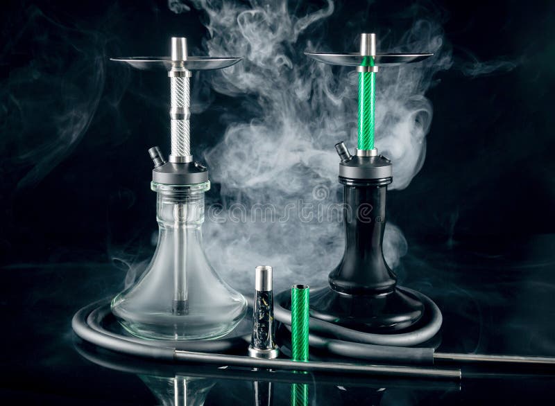 Dos hookahs modernos con humo en el fondo de un espejo negro.