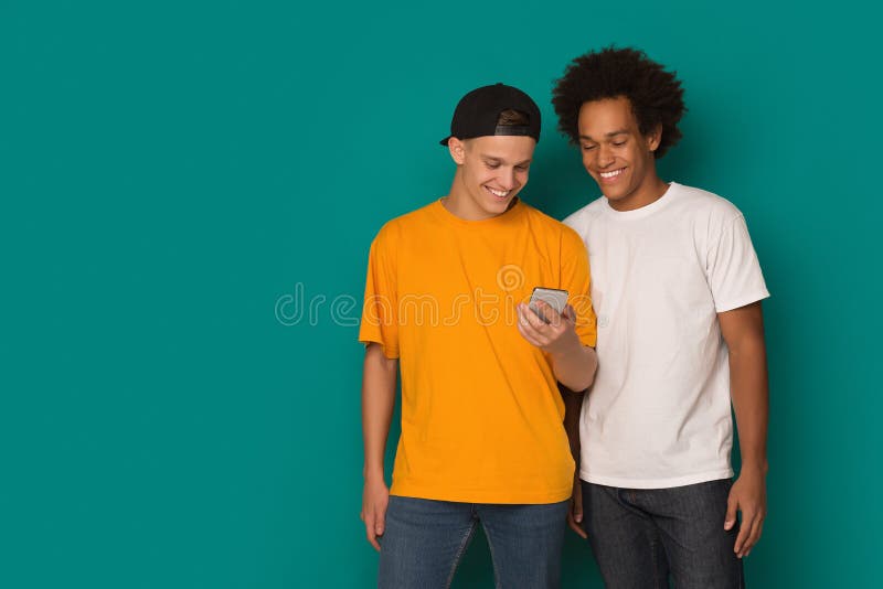 Dos individuos adolescentes que usan smatphone en fondo azul fotografía de archivo libre de regalías Dos individuos adolescentes que usan smatphone en fondo azul fotografía de archivo libre de regalías