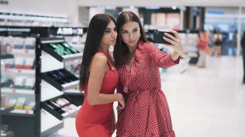 Dos Jovencitas Bonitas Se Hacen Selfie Por Smartphone En El Centro Comercial Almacen De Video - Vídeo de surtido, novias: 209055713