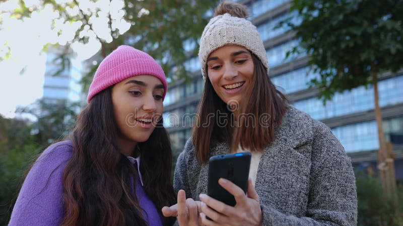 Dos jóvenes adultas mirando el teléfono discutiendo sobre noticias en medios sociales