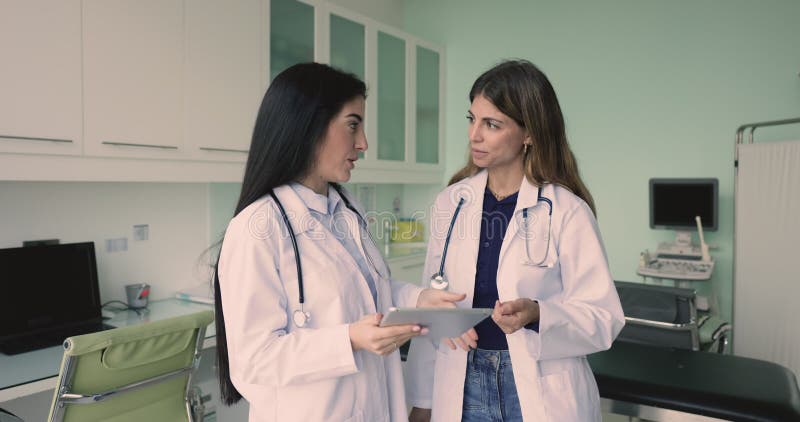 Dos jóvenes doctoras hispanas hablando en la oficina de escaneo de ultrasonidos almacen de video