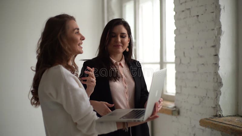 Dos jóvenes empresarias que se reúnen y conversan con una laptop. metrajes