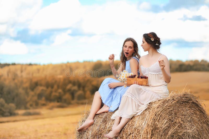 Dos muchachas en vestidos en campo del otoño foto de archivo