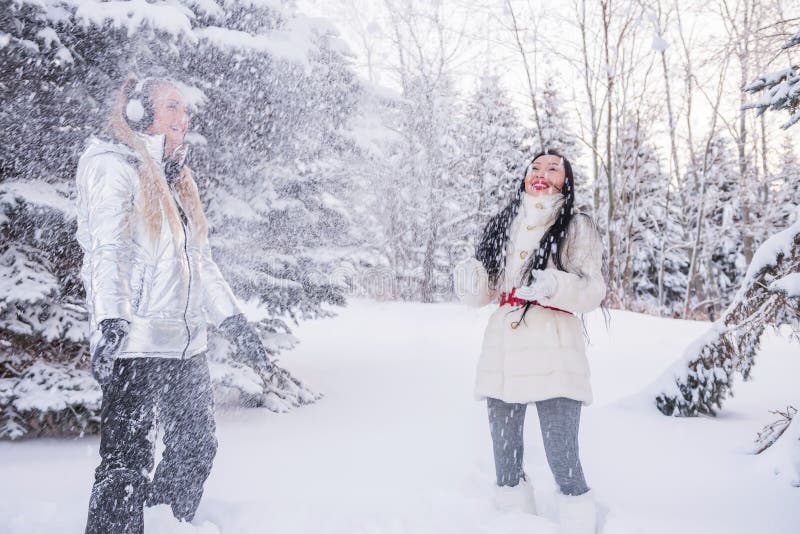 Dos muchachas que se divierten en la nieve entre los árboles La atmósfera de la diversión y de la relajación del invierno imágenes de archivo libres de regalías