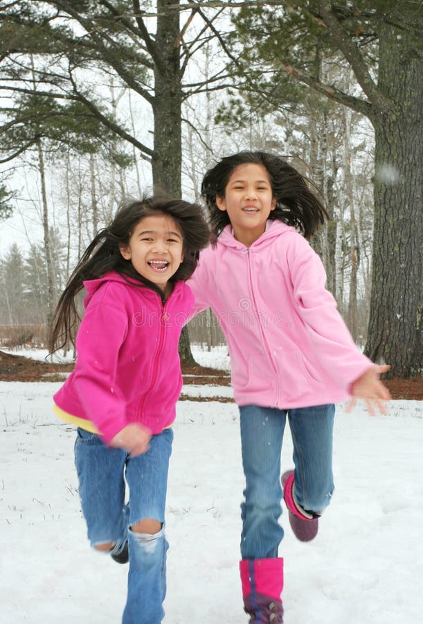 Dos muchachas que se ejecutan a través de la nieve