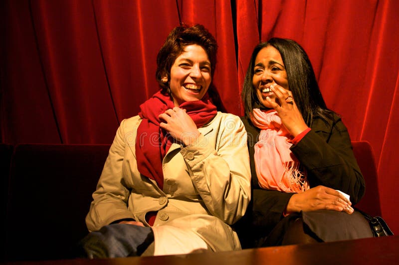 Dos muchachas que se ríen del teatro con una cortina roja en la parte posterior fotos de archivo Dos muchachas que se ríen del teatro con una cortina roja en la parte posterior fotos de archivo