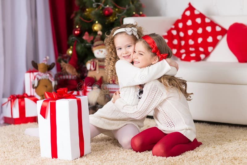 Dos muchachas rizadas adorables que juegan con la caja de regalo