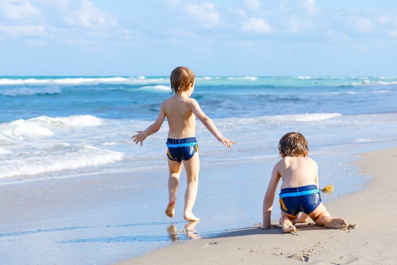 Dos muchachos del niño que corren en el océano varan en la Florida imágenes de archivo libres de regalías Dos muchachos del niño que corren en el océano varan en la Florida imágenes de archivo libres de regalías